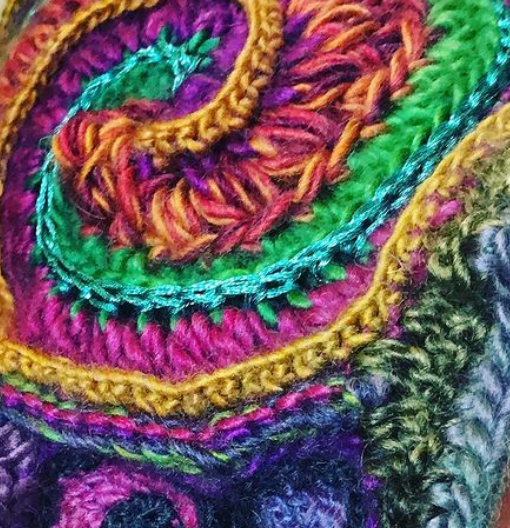 close up image of freeform crochet in a spiral shape with lots of different colour yarns and textures